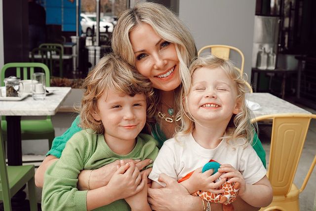 Vanessa Lee Evigan in a green dress posing with her son in a light green t-shirt and her daughter in a white t-shirt.